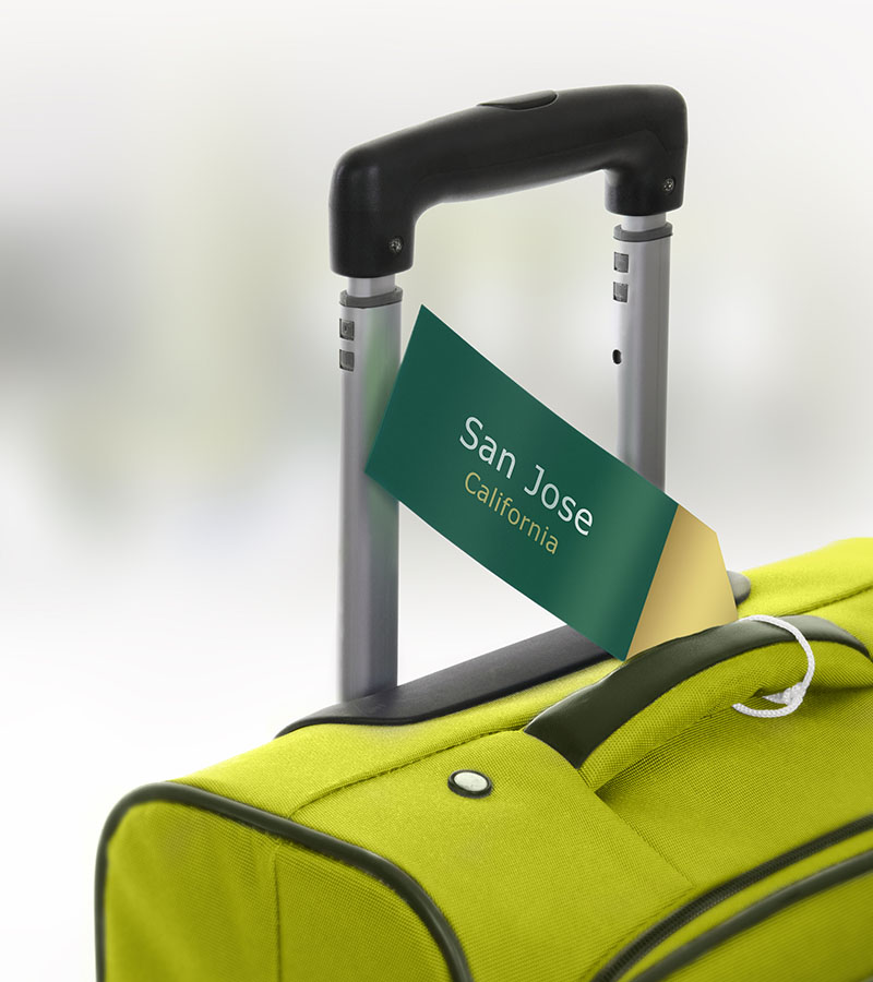San Jose, California. Green suitcase with label at airport.